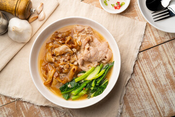 Flat Noodles with Marinated Pork and Collard greens in Gravy Sauce in white plate.Top view