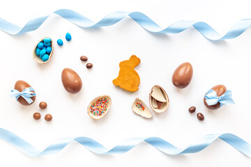 Obraz na płótnie Canvas Easter background. Chocolate Easter eggs in blue ribbon with bunny cookies