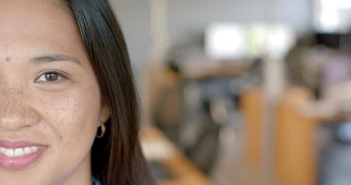 Close-up of an Asian business woman smiling in an office environment with copy space