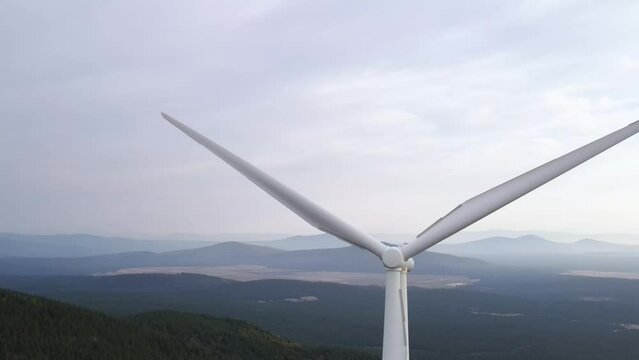 Aerial shot of a row of wind turbines along the ridge of a mountain