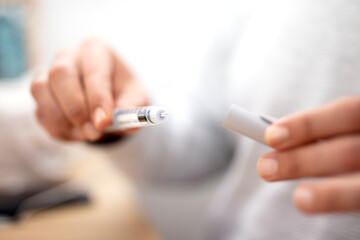 Diabetes patient turn knob on end of insulin pen 