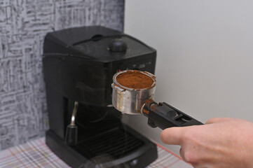 a woman's hand puts ground coffee in the coffee machine