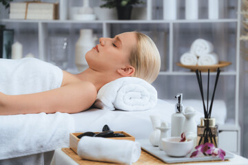 Obraz na płótnie Canvas Caucasian woman customer enjoying relaxing anti-stress spa massage and pampering with beauty skin recreation leisure in day light ambient salon spa at luxury resort or hotel. Quiescent