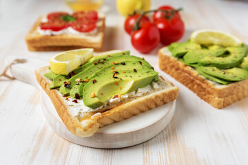 Sliced avocado on toast bread with spices on white wooden background. Food concept.