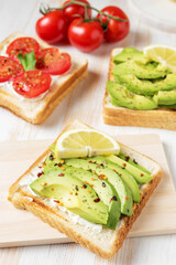 Sliced avocado on toast bread with spices on white wooden background. Food concept.