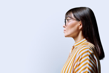 Profile view of middle aged serious woman, white background, copy space