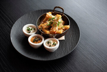 Gourmet fries with sauce on black plate