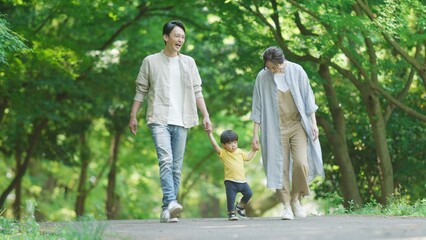 手を繋いで公園を歩く家族