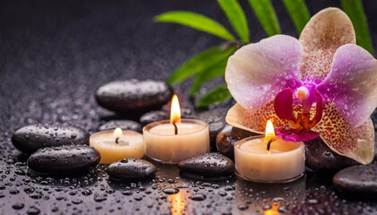 Beautiful spa background with massage stones, candles, pink orchid and drops of waters on black backdrop.