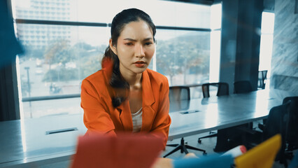 Professional young beautiful businesswoman thinking while standing at glass board with colorful...