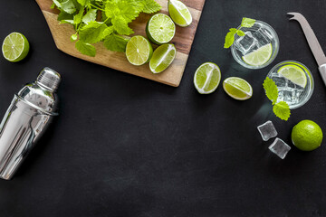 Bartender desktop with utensils and mojito cocktail. Lime with mint and ice cubes, top view