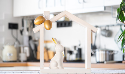 Tiny house of cozy home with Easter decor with rabbit and eggs on table of kitchen. Building,...