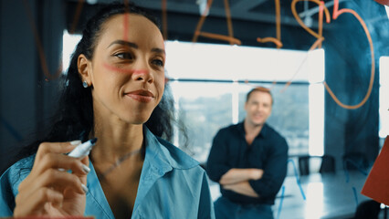 Smart businesswoman leader writing creative business idea while male caucasian investor listen...