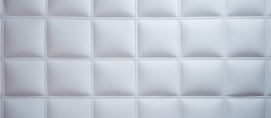 A detailed view of a white tiled wall showcasing its square and linear texture. The tiles are neatly arranged, creating a clean and uniform surface.