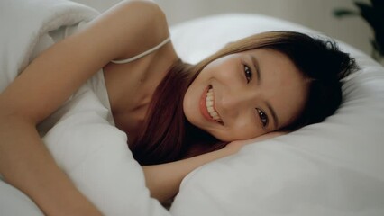 Wake up moment of Beautiful asian woman after have sweet dreams and deep sleep in bed comfortably with pillows. She sleeping on white bedding in light bedroom in morning. Have a good day.