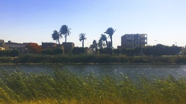 June 1, 2021 - Cairo to Luxor Train Line, Egypt. The view from the train carriage window as it travels along the Nile River in rural Egypt.