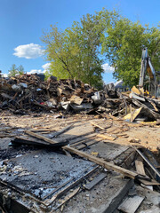 Remains of a building destroyed by fire. Demolition site with a bulldozer. Pile of debris after a sinister. Clean-up and rebuilding site after an incident.
