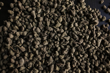 Pile of small brown rocks resembling a pattern on black flooring