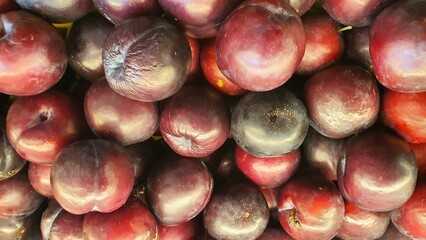 Close up pile of tasty fresh plums sold at the market as a background.