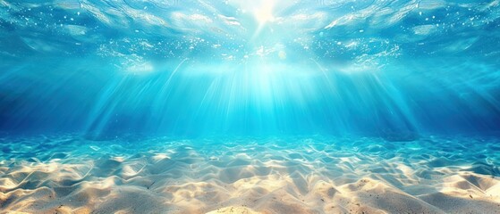 an underwater view of a sandy beach with sunlight streaming through the water and sand under the water's surface.