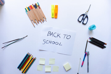 School accessories on a white background and white paper in the middle with 