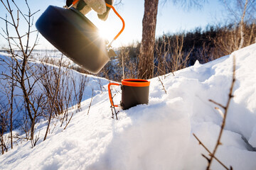 kettle against the background of the glare of the sun, camping equipment, utensils on a winter...