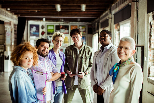Diverse and multigenerational group of people looking at the camera while working in a startup company office