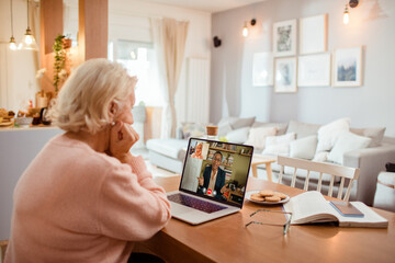 Senior woman on a video call with financial advisor using a laptop at home