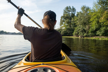 Male kayaker adeptly handles kayak on lake showing confidence in navigating. Man enjoys sunny day...