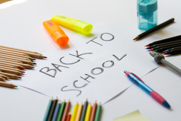 school accessories on a white background and white paper in the middle with "back to school' text on it. Concept for back to school, 