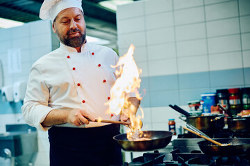 Professional cook preparing dish while working in kitchen at restaurant.