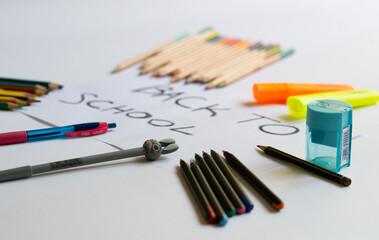 school accessories on a white background and white paper in the middle with "back to school' text on it. Concept for back to school, 