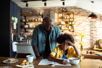 Father helping son with homework in kitchen