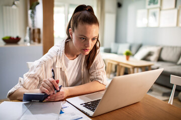Stressed young woman working on laptop at home