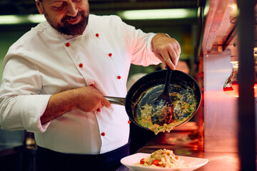 Happy professional cook working in restaurant kitchen.