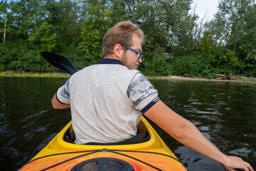Man exhibits skillful maneuvering in kayak crossing lake. Sportsman shows ability to navigate...