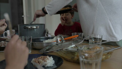 Candid Family Lunch Scene, Young Girl Engaged in Meal Cutting and Observing Family Interactions
