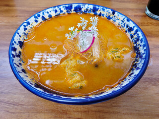 Hearty menudo soup, a Mexican culinary staple, garnished with fresh herbs