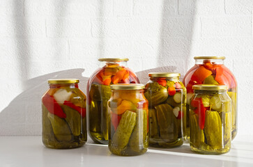 Glass jars with canned tomatoes and cucumbers on a white background. Close up. Copy space.