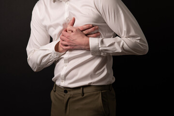 young man in formal office clothes having chest pain, and holdign two hands on chest.