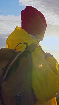 Slow motion camera follows woman hiker in yellow raincoat with backpack. Attractive happy young girl with backpack hiking. Setting sun on the horizon in the mountains of Madeira island