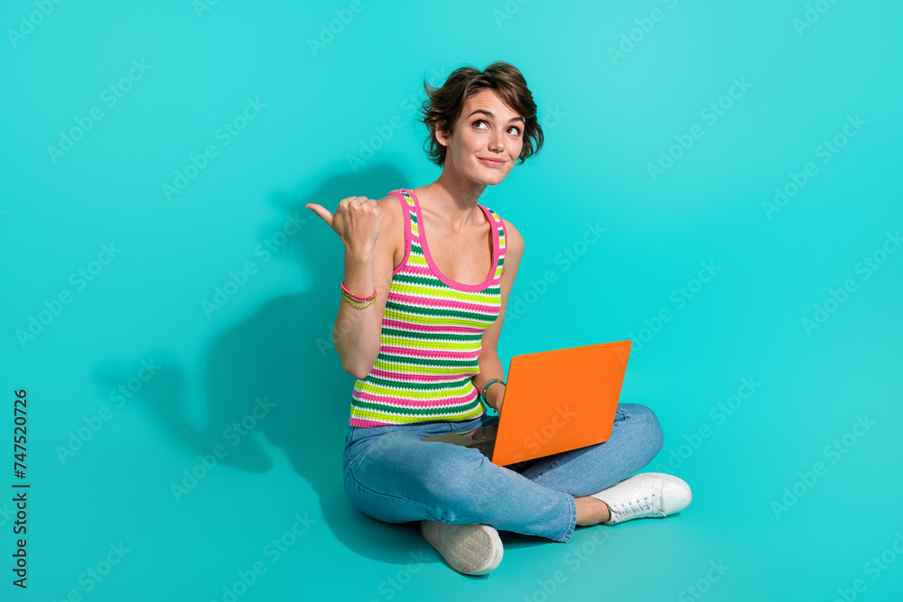 Canvas Prints Full length portrait of lovely person sit floor use laptop look indicate finger empty space isolated on turquoise color background