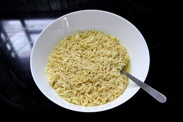 A bowl of cooked instant ramen noodles with a fork