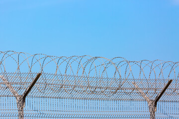 Fence with barbed wire against blue sky. Prison or restricted area concept