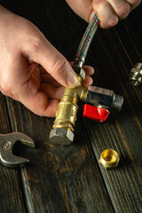 A plumber connects brass fittings to a high pressure water hose. Close-up of a craftsman hand while working on a table in a workshop. Advertising space