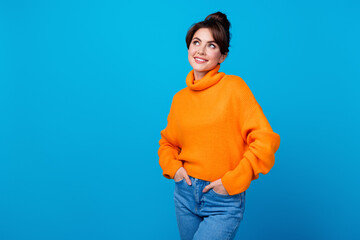 Photo of positive dreamy woman dressed orange sweater looking empty space isolated blue color...