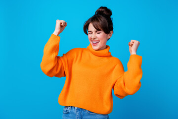 Photo of lucky impressed woman dressed orange sweater closed eyes screaming yeah rising fists...