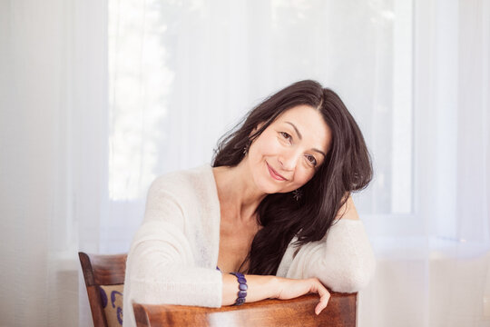 Serene lady lost in thought, gentle smile, possible emotional changes, bright indoor ambiance, reflecting lifes and hormonal transitions, copy space.