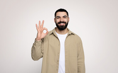 Confident young man with a beard making an 'excellent' sign with his hand