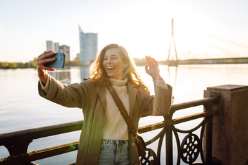 Happy woman with a mobile phone, takes a selfie, communicates with friends, blogs outdoor....